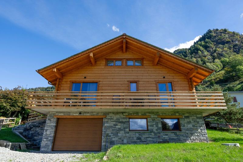 Il lato sud dello chalet con il terrazzo coperto in legno sopra il basamento in pietra