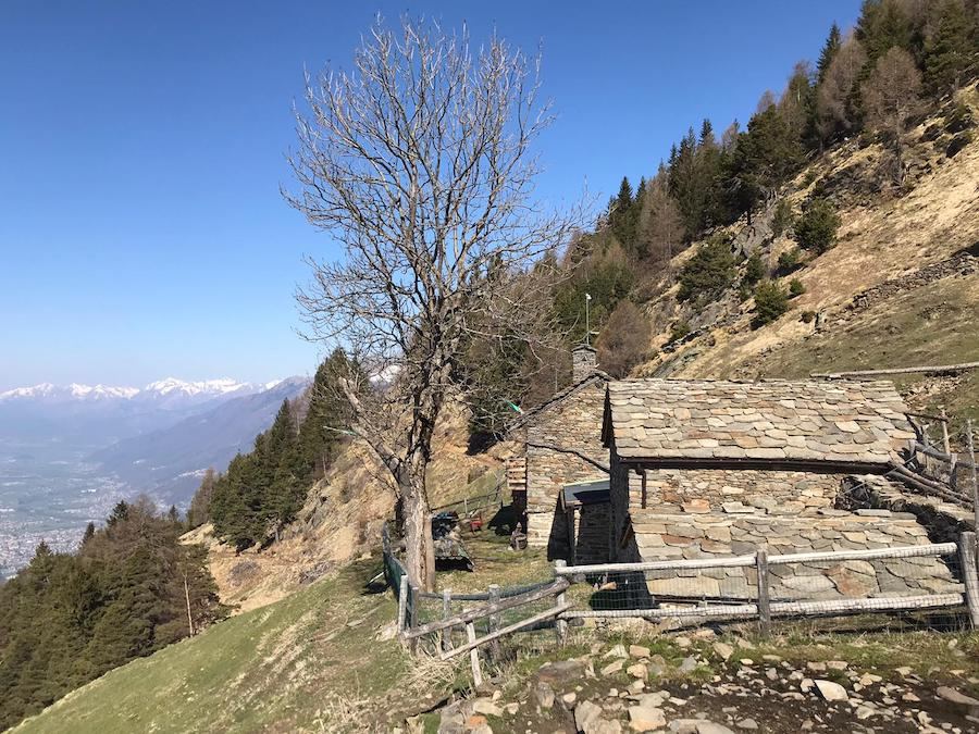 Una baita in pietra sul pendio dell’alpe, con la valle sotto
