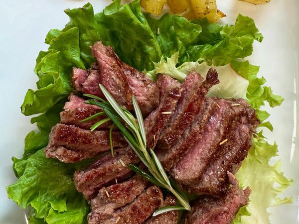 Tagliata di carne Highland con rosmarino su un letto di insalata, servita al ristoro