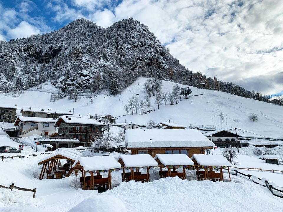 Il dehors del ristoro e il paese sotto la neve, con la montagna innevata dietro